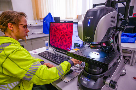 Laboratory worker with microscope in ITC in Villach, Austria - Imerys