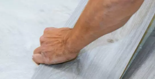 Worker installing new vinyl tile floor 
