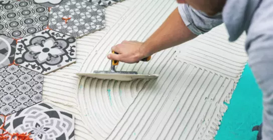 Worker applying tile adhesive on floor